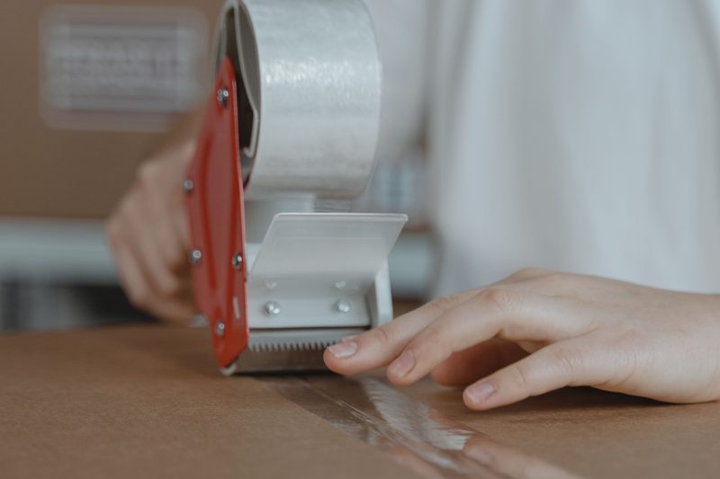 Una dispensatrice di nastro adesivo che chiude una scatola di cartone